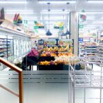 Vibrant fruit display in a well-lit supermarket aisle with fridges and shelves.