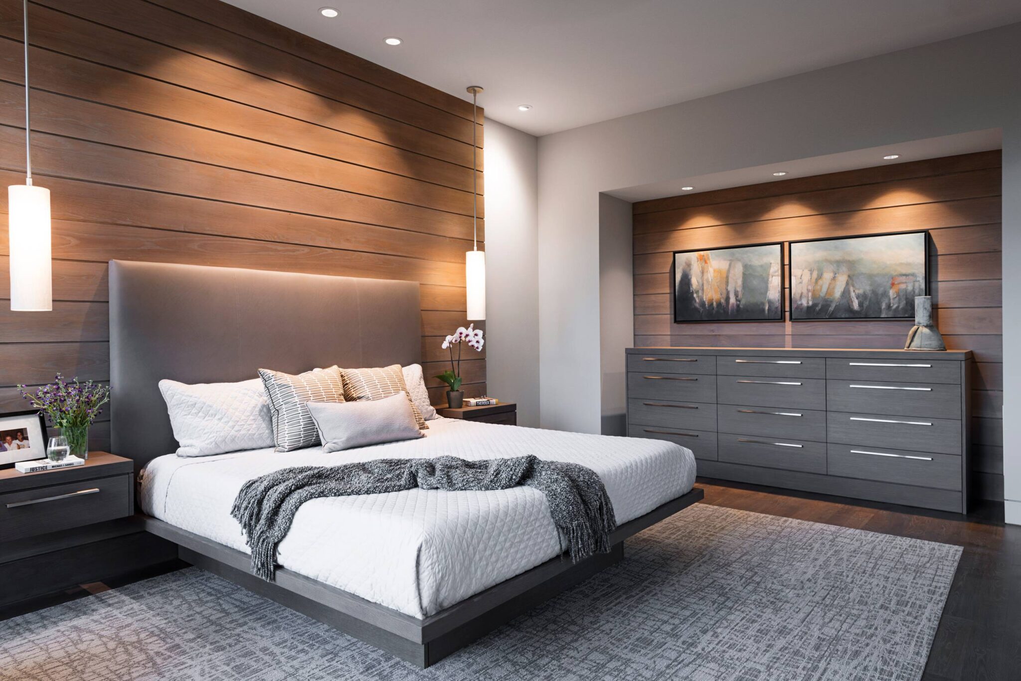 An elegant master bedroom showcasing a tall upholstered headboard, soft neutral colors, ambient lighting, and minimalist décor that enhances comfort and visual balance.